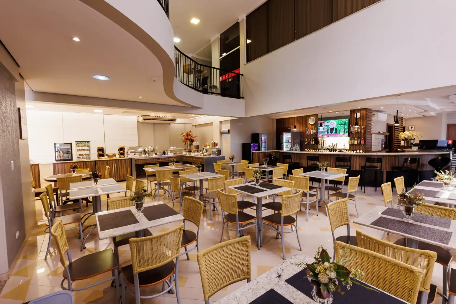 Salão do restaurante do Tonello Business Hotel com mesas, cadeiras e bar ao fundo